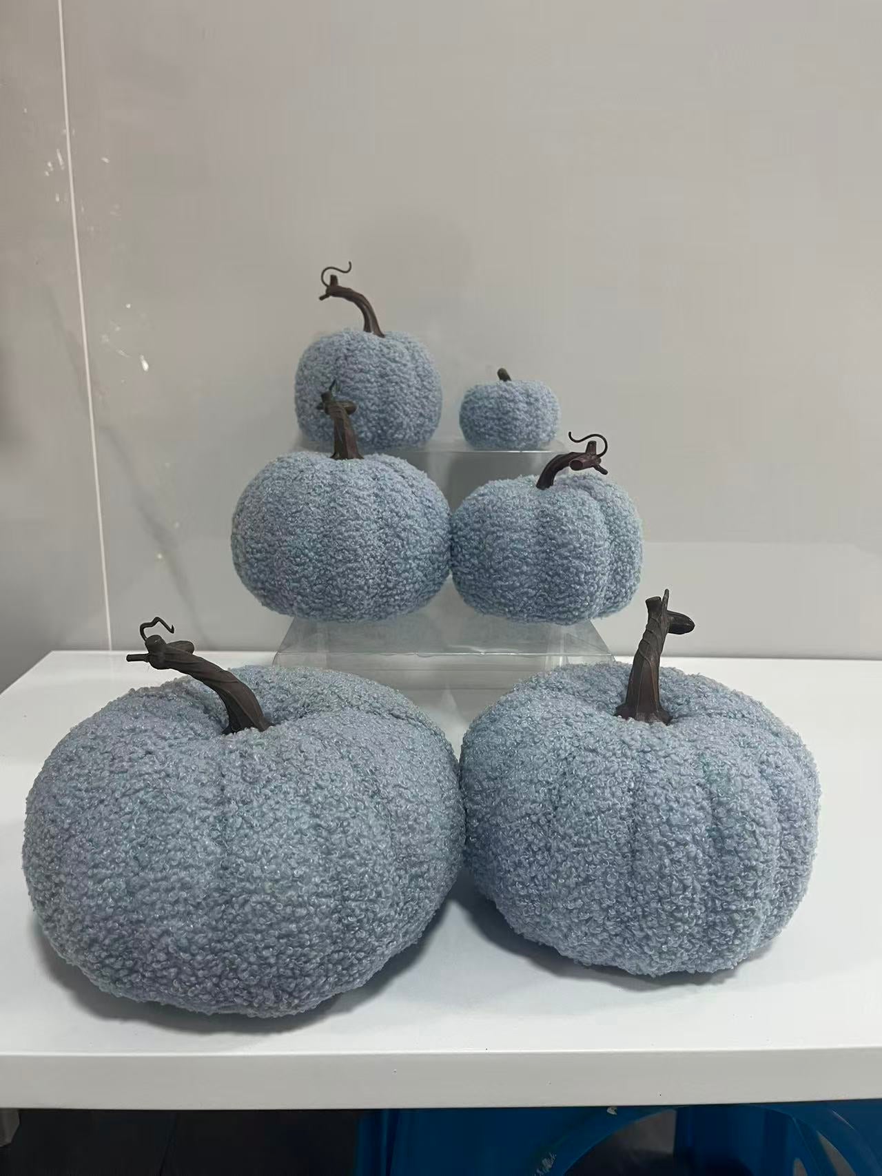 A collection of light blue Sherpa pumpkins in various sizes with realistic brown stems, featuring a soft boucle fabric texture for modern fall and Halloween home styling.
