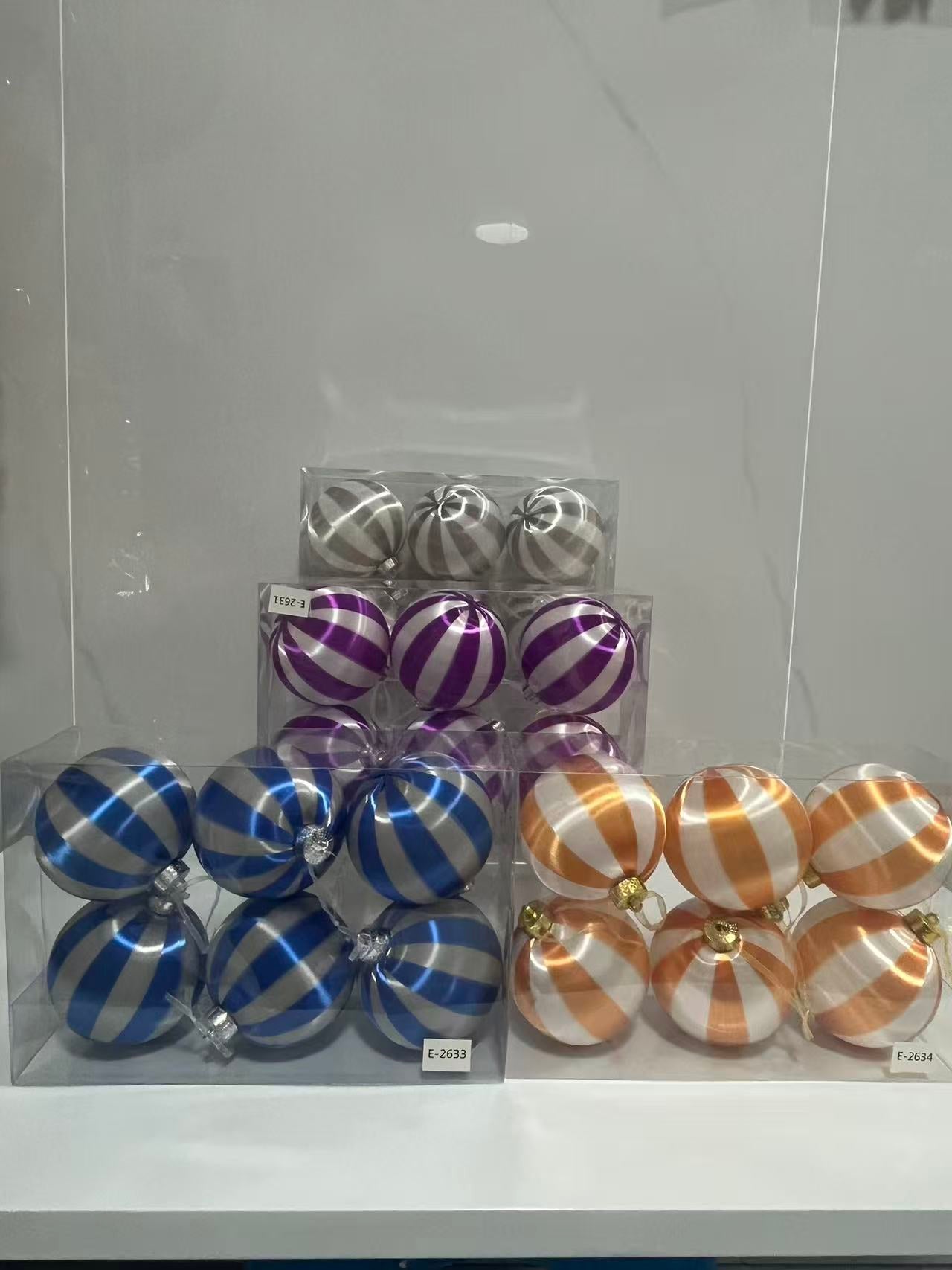 Assorted sets of hand-wound silk Christmas ball ornaments with elegant striped patterns in silver, purple, blue, and gold, packaged in clear display boxes for holiday retail.
