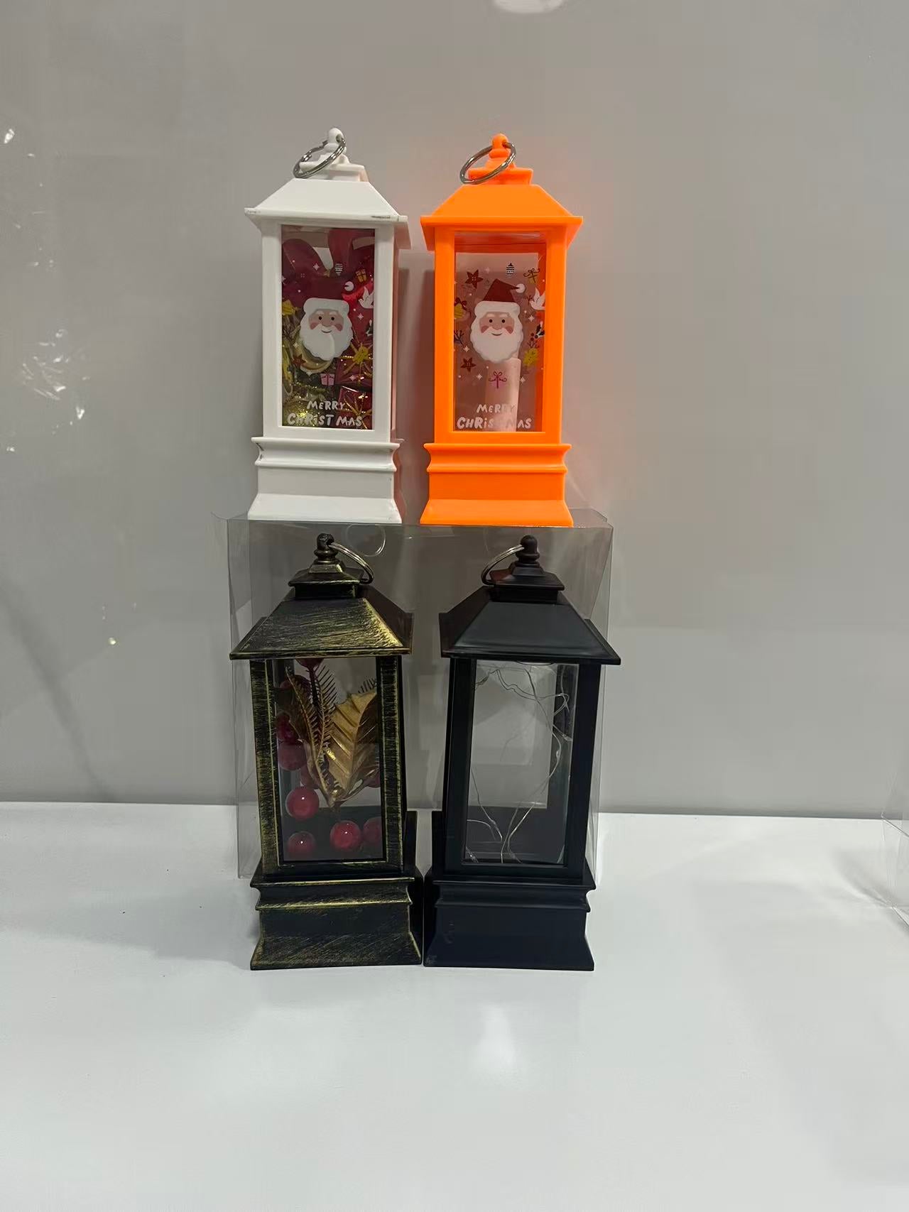 Four mini Christmas lanterns in white, orange, and black, featuring Santa Claus illustrations and decorative elements, designed with hanging rings for festive holiday display.